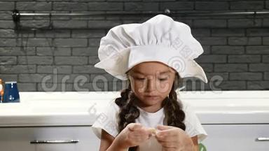 小美女戴着厨师帽玩面团的肖像，孩子在真正的厨房做饭。 4k